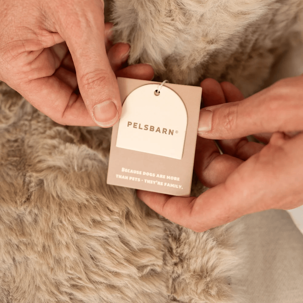 Hands holding the Pelsbarn tag on a faux fur bed